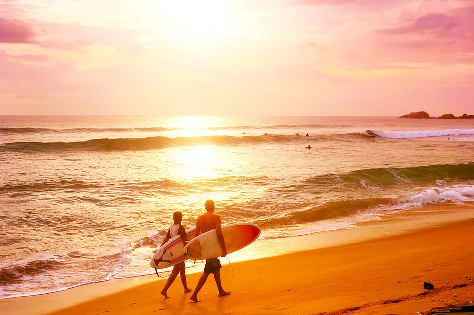 Couple with surfboards at sunset